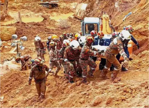  ??  ?? Tragic retrieval: Fire and rescue personnel carrying away Yuan’s body from the scene of the landslide.