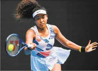  ?? William West / AFP via Getty Images ?? Defending champion Naomi Osaka hits a return during a 62, 64 win over Marie Bouzkova on Day 1 of the Australian Open in Melbourne. Osaka will face Saisai Zheng in the second round.