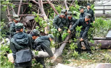  ??  ?? Chinese paramilita­ry police officers clearing branches on a road, a day after Typhoon Mangkhut hit in Zhongshan, in China’s southern Guangdong province. — AFP photo