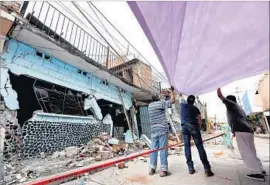  ?? Gary Coronado Los Angeles Times ?? NEIGHBORS place a tarp over part of the street near Maria Elena Jimenez Arizmendi’s home, which was destroyed in Tuesday’s earthquake in Jojutla, Mexico.