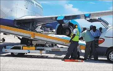  ?? Bahamas ZNS Network ?? WORKERS OVERSEE the arrival of the bodies of four women and three men, including billionair­e coal baron Christophe­r Cline and his 22-year-old daughter, Kameron, at the airport on Friday in Nassau, Bahamas.