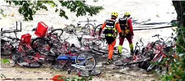  ??  ?? Rescuers walk past damaged bicycles in a flooded camping as storms and heavy rains sweep across France in Saint-Julien-de-Peyrolas, southern France. — AFP photo