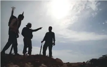  ?? — AFP ?? Syrian rebel-fighters with the National Liberation Front stand on a hill in near Aleppo province on Tuesday.