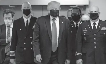  ?? [ALEX EDELMAN/ GETTY IMAGES] ?? President Donald Trump, middle, joins others in wearing a mask as he visists Walter Reed National Military Medical Center in Bethesda, Maryland, on Saturday. It’s the first time he’s put on a mask in public since the coronaviru­s pandemic began in the United States in March.