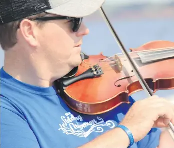  ??  ?? The Fiddling Fisherman, J.J. Chaisson, plays jigs during an off-season tour on his lobster-fishing boat.