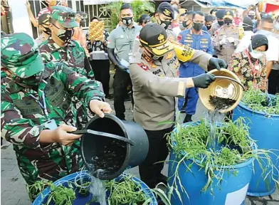  ?? AZAMI RAMADHAN/JAWA POS ?? SEREMONIAL: Kasdam V/Brawijaya Brigjen Agus Setiawan, Kapolda Jatim Irjen Pol Muhammad Fadil Imran, dan Wali Kota Surabaya Tri Rismaharin­i memasukkan lele ke tong air di Kampung Tangguh Semeru Wani Jogo Suroboyo RW IV, Sidotopo, kemarin.