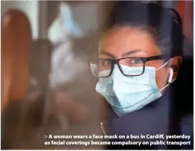  ??  ?? > A woman wears a face mask on a bus in Cardiff, yesterday as facial coverings became compulsory on public transport