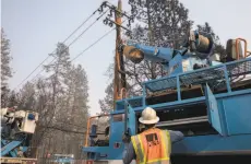  ?? Jessica Christian / The Chronicle 2018 ?? PG&E crews clear downed power lines and telephone poles in Paradise in November after the destructiv­e and deadly fire.