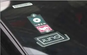  ??  ?? The Uber, Lyft and Juno logos are seen on a car in New York City. Uber and Lyft are driving side-by-side on the road to a stock market debut, and that may not bode well for Lyft as investors decide where to place their bets in the ride-hailing sector.