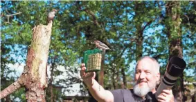  ?? MICHAEL KOPACK III VIA AP ?? Amateur bird watcher Michael Kopack Jr. holds his camera while two nuthatches land nearby in Angier, N.C., earlier this year.