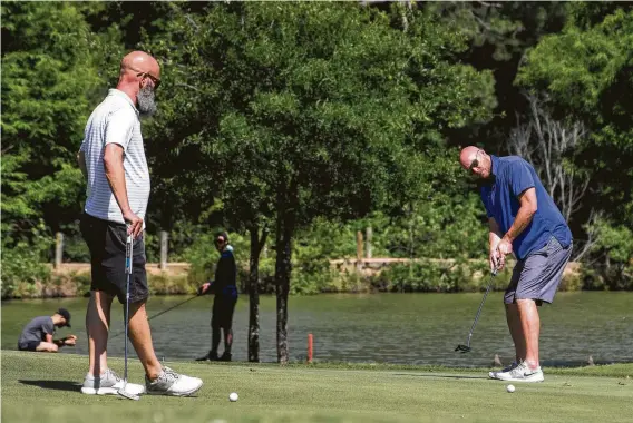  ?? Brett Coomer / Staff photograph­er ?? Brett Skiles, left, and Rob Williams play a round at Hermann Park Golf Course, which had been closed for about six weeks before reopening Friday.