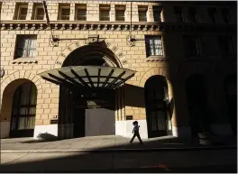  ?? NOAH BERGER — THE ASSOCIATED PRESS FILE ?? A pedestrian passes a boarded-up entrance to the Omni San Francisco Hotel, which has suspended operations due to the COVID-19 pandemic.