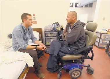  ?? ADOLPHE PIERRE-LOUIS/JOURNAL ?? UNM medical student Cody Fritts, left, talks with James Christian, a homeless man with diabetes, at an AOC clinic. Due to his diabetes, Christian has lost the lower part of his right leg, his right index finger and all the toes on his left foot to...