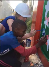  ??  ?? Leah painting with one of the local children during the visit to their school.