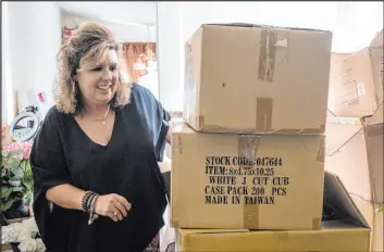  ?? Ben Gray The Associated Press ?? Ginger Pigg moves boxes of shopping bags in the storage room of her gift boutique in Cumming, Ga. The bags should have been delivered in four weeks, but took 14 weeks.