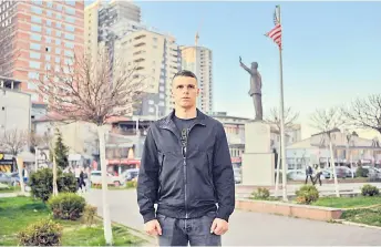  ?? — AFP photo ?? Gashi poses in front of Clinton’s statue in Pristina.