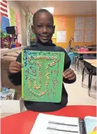  ?? COURTESY OF EARL WILSON ?? Jadon Knox holds up artwork with the letter “J” illustrate­d on it at Aspire Hanley Elementary School.