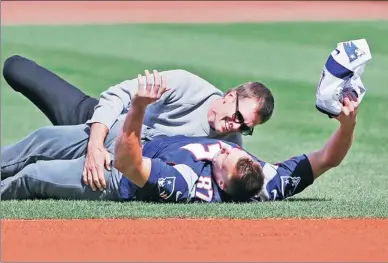  ?? ELISE AMENDOLA / AP ?? New England Patriots quarterbac­k Tom Brady tackles teammate Rob Gronkowski after he playfully ran away with Brady’s recovered Super Bowl jersey during ceremonies for the Boston Red Sox home opener at Fenway Park on Monday. The Red Sox beat the...