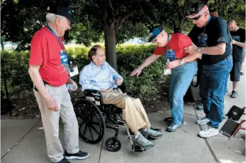  ?? CITIZEN NEWS SERVICE PHOTO BY CHERYL DIAZ MEYER ?? Navy veteran Leon Brooks of Nevada, second from right, gets out of his wheelchair to greet former Senator Bob Dole while Air Force veteran James Howerton, far left, watches, at the National World War II Memorial during an Honor Flight trip to...