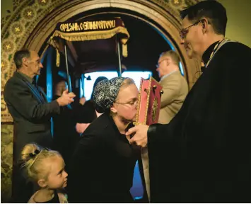  ?? WONG MAYE-E/AP ?? A little girl watches as her mother kisses the Gospel book as she enters St. Mary’s Ukrainian Orthodox Cathedral in Allentown, Pennsylvan­ia, for a Good Friday service.