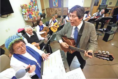  ?? MIKE DE SISTI / MILWAUKEE JOURNAL SENTINEL ?? Alberto Cardenas (right), Grupo Renacer director, works with Maria de Jesus Valencia. Grupo Renacer, a band whose members attend the United Community Center’s senior center, were rehearsing at the UCC on S. 9th St. in Milwaukee.