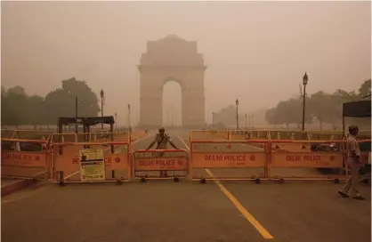  ?? —AP photos ?? NEW DELHI: A Delhi policeman stands guard at the war memorial India Gate engulfed in a thick smog in New Delhi, India, yesterday.