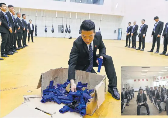  ??  ?? LEFT
A trainee selects a model gun during a training session at the Genghis Security Academy.