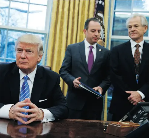  ?? EVAN VUCCI / THE ASSOCIATED PRESS ?? National Trade Council adviser Peter Navarro, right, and White House Chief of Staff Reince Priebus, centre, await President Donald Trump’s signing of three executive orders on Jan. 23.