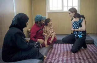  ??  ?? ANGELINA JOLIE sostiene a un niño al visitar a una familia de refugiados sirios en su apartament­o de Amman.