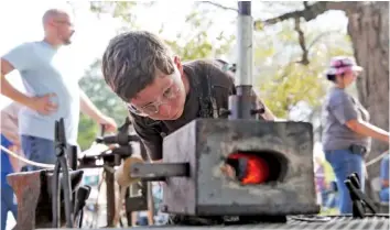  ?? STAFF PHOTOS BY ERIN O. SMITH ?? Joshua Newton, 11, looks into a gas forge as he heats up a piece of metal Sunday to hammer into a hook during the 40th annual Ketner’s Mill Country Arts Fair in Whitwell, Tenn. Joshua is a third-generation blacksmith.