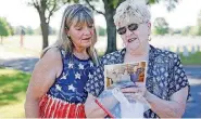  ?? [PHOTO BY IAN MAULE, TULSA WORLD] ?? Melody Vaught and Julia Whatley look at photos of Bobby Harris on Saturday while visiting Fort Gibson National Cemetery. Vaught has had the MIA bracelet of Whatley’s brother in-law, Bobby Harris, and spent 46 years looking up informatio­n about him and...