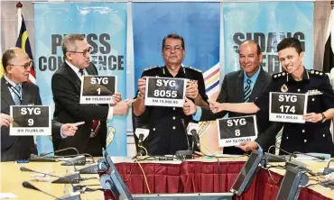  ??  ?? Numbers for sale: Shaharuddi­n (centre) and other JPJ officers showing the ‘SYG’ registrati­on numbers which secured the highest bidders.