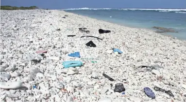  ?? THOMAS WATKINS/AFP/GETTY IMAGES ?? Plastic trash is strewn across a beach at Wake Island in the western Pacific Ocean. Residents continuall­y comb the beach for waste, but more washes up daily.