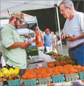 ?? Agnes Hagin/SJ ?? Jason Cook, left, Spreading Oaks Farm, assists Jere Wilson, who purchased fresh tomatoes at Rockmart Farmers Market.