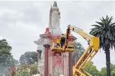  ?? Photo — AFP ?? A council worker cleans the statue to Queen Victoria that was defaced in the Royal Botanic Gardens Victoria in Melbourne ahead of Australia Day.