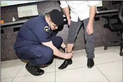  ??  ?? Top and above: MoI officers give a demo on how the tracking bracelets are installed on a prisoner.