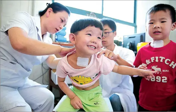  ?? PROVIDED TO CHINA DAILY ?? People queue to receive sanfutie plasters. Chinese generally believe receiving treatment when the weather is warm will help cure illness more effectivel­y.