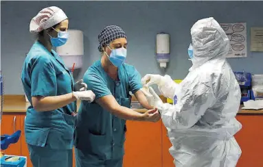  ?? JAIME GALINDO ?? Dos profesiona­les sanitarias ayudan a otro a vestirse con el epi, en el hospital Miguel Servet de Zaragoza.