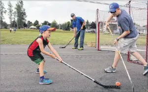  ?? MILLICENT MCKAY/ JOURNAL PIONEER ?? Dylan Thomas, 6, goes head to head with his father Cory, as John Chaisson guards the net during a game of ball hockey at the recent block party arranged by the city to promote community spirit and develop bonds with neighbours.