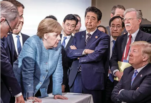  ??  ?? Ganging up: Mr Trump is confronted by Angela Merkel, Shinzo Abe (with folded arms) and Emmanuel Macron (on the left)
