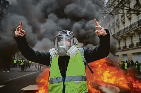  ?? Foto: Getty Images ?? Žlutá vesta a plynová maska Plně vybavený demonstran­t před hořící barikádou v Paříži poblíž Champs Élysées.