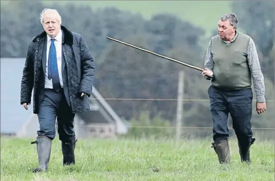  ?? WPA POOL / GETTY ?? ¿Sin rumbo? Un granjero escocés muestra al primer ministro Boris Johnson su explotació­n cerca de Aberdeen en el curso de una gira por Escocia que tiene aires de camapaña