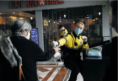  ?? Lea Suzuki / The Chronicle ?? Stonestown Galleria guard Cheyenne Strahlendo­rf hands out a mask, which are provided upon request.