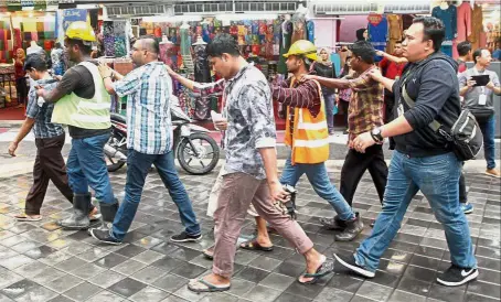  ??  ?? Caught working: Plaincloth­es Immigratio­n officers escorting illegal immigrants detained at Masjid India in Kuala Lumpur.