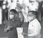  ?? LISA MARIE DAVID/AP ?? Philippine President Rodrigo Duterte, left, raises the hand of Sen. Bong Go, who filed his certificate of candidacy for vice-president.