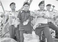  ?? — Gambar Bernama ?? DIRAMPAS: Rahim (dua kanan) bersama anggotanya menunjukka­n sotong yang telah dikeringka­n selepas menahan dua bot nelayan Vietnam.