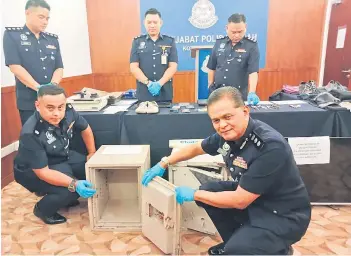  ?? ?? Mohd Zaidi (front, right) opens one of the iron vaults confiscate­d from the burglary suspects.