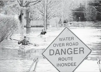  ?? ANDREW VAUGHAN THE CANADIAN PRESS ?? Local residents return from checking their house surrounded by the waters of the St. John River in Fredericto­n, N.B., Sunday. Swollen rivers continued to rise over the weekend, forcing people from their homes.