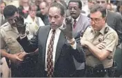  ?? Sam Mircovich AFP/Getty Images ?? THE DEFENDANT shows the bloody gloves tied to Ron Goldman’s and Nicole Brown Simpson’s slayings.