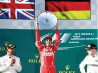  ?? – Reuters ?? POSITIVE SURPRISE: Ferrari’s Sebastian Vettel, centre, celebrates alongside Mercedes’ Lewis Hamilton, left, and teammate Valtteri Bottas after winning the Australian GP in Melbourne on Sunday.